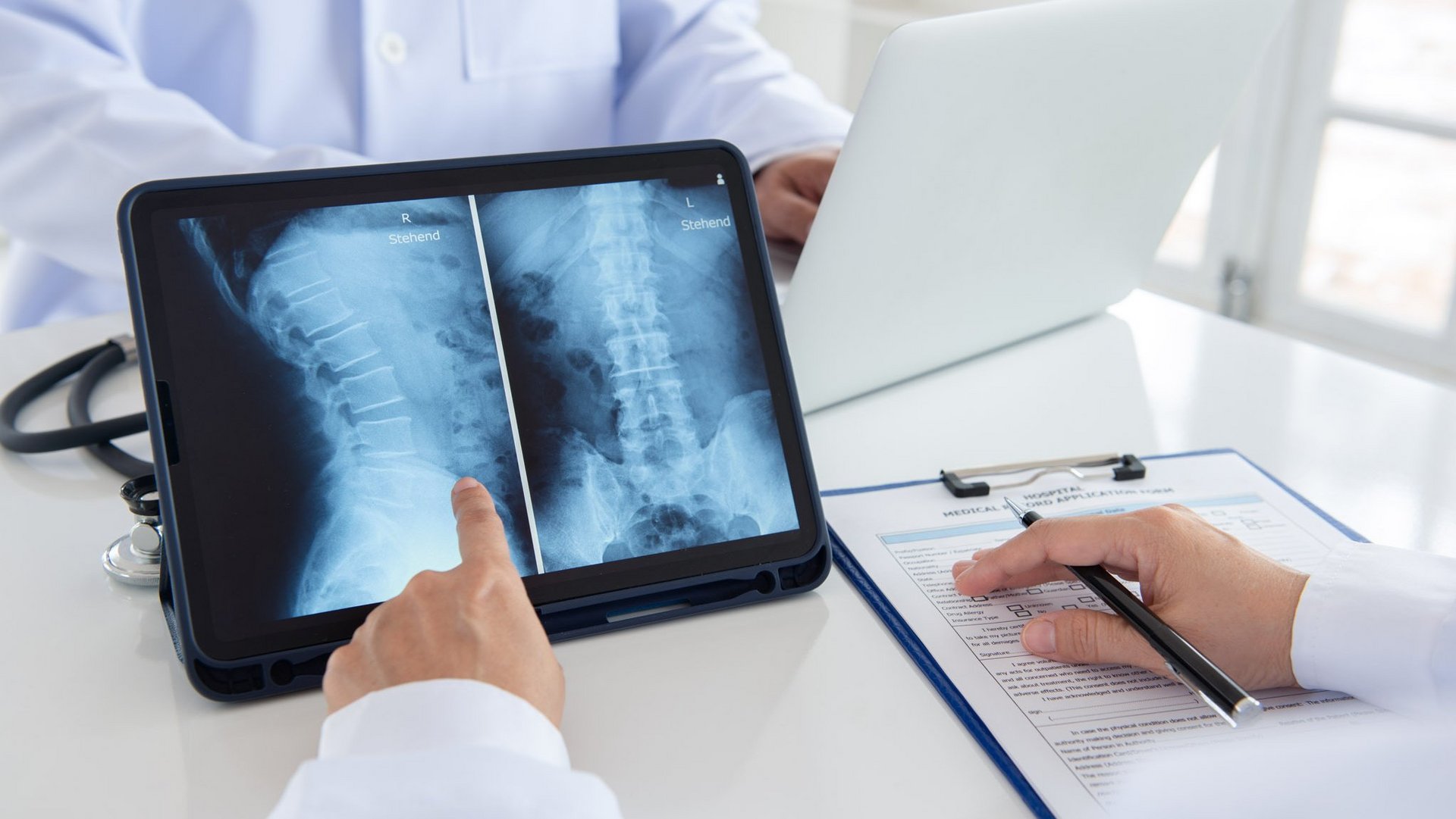 facet-si-joint-syndrome-xray-diagnosis-riwospine.png Doctors analyzing spinal X-rays for facet or SI joint syndrome diagnosis